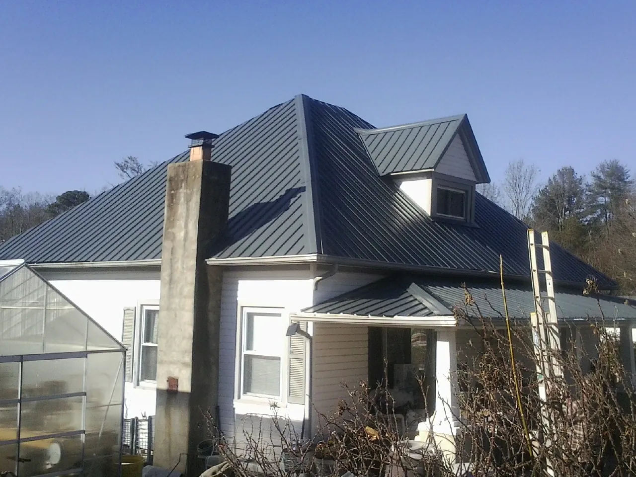 Dark blue standing seam metal roof on a white farmhouse with dormer — Slate & Tile Roof Repair by Roofing Brothers in Dowelltown