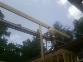 Carpenter setting a ridge beam over a new addition frame — Ice Dam Removal by Roofing Brothers in Dowelltown