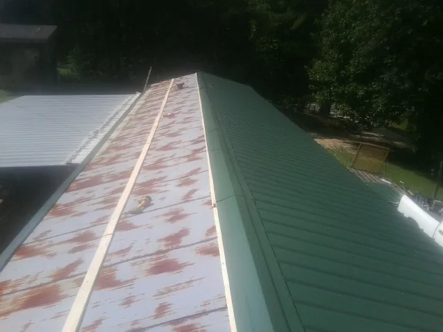 Old rusted panels beside newly installed green metal roofing — Wind Damage Roof Repair by Roofing Brothers in Dowelltown