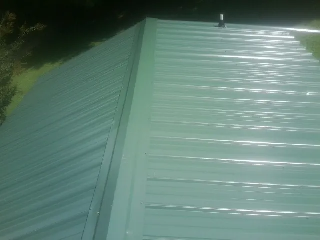 New green metal panels meeting at the ridge of a roof — Flat Roof Repair work by our crew in Dowelltown
