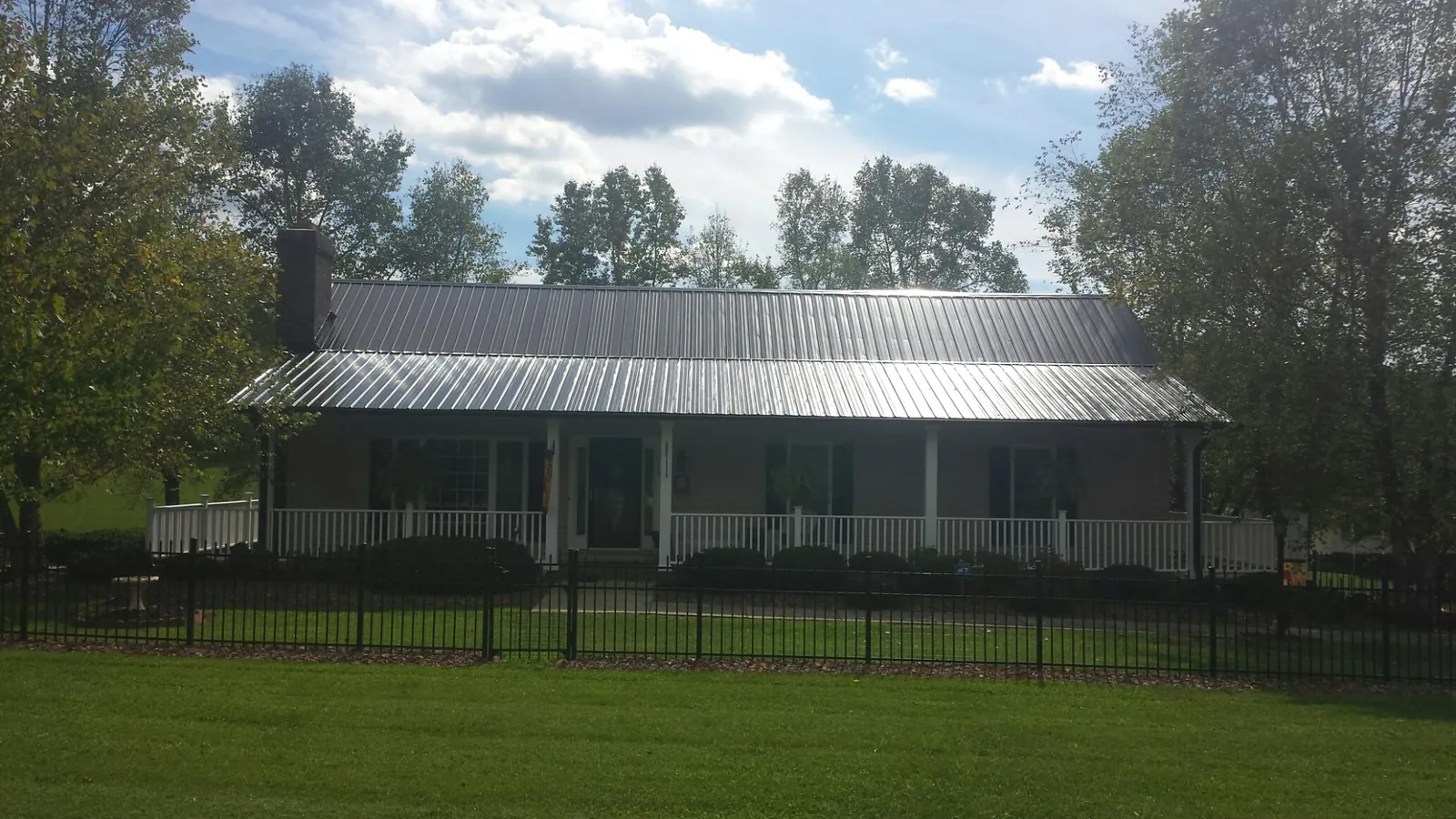 Gray metal roof on a brick ranch with a full width front porch — Gutter Guard Installation work by our crew in Dowelltown