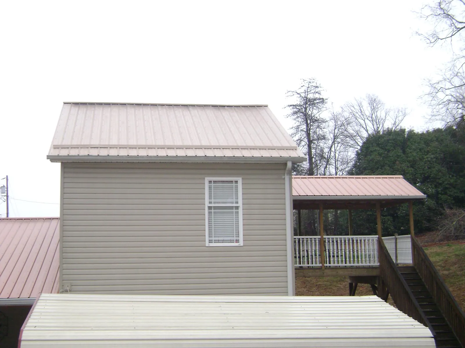 Tan metal roofs on a two story addition and attached porch, from a Roof Replacement job in Dowelltown