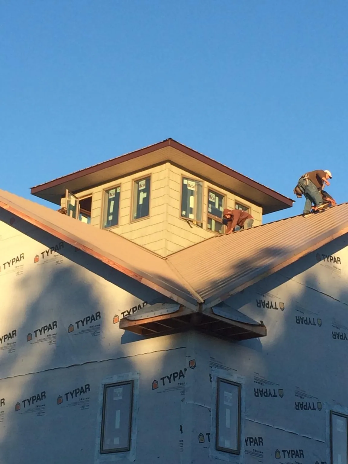 Roofers working around a rooftop cupola on a new metal roof at sunset — Roof Waterproofing in Dowelltown by Roofing Brothers